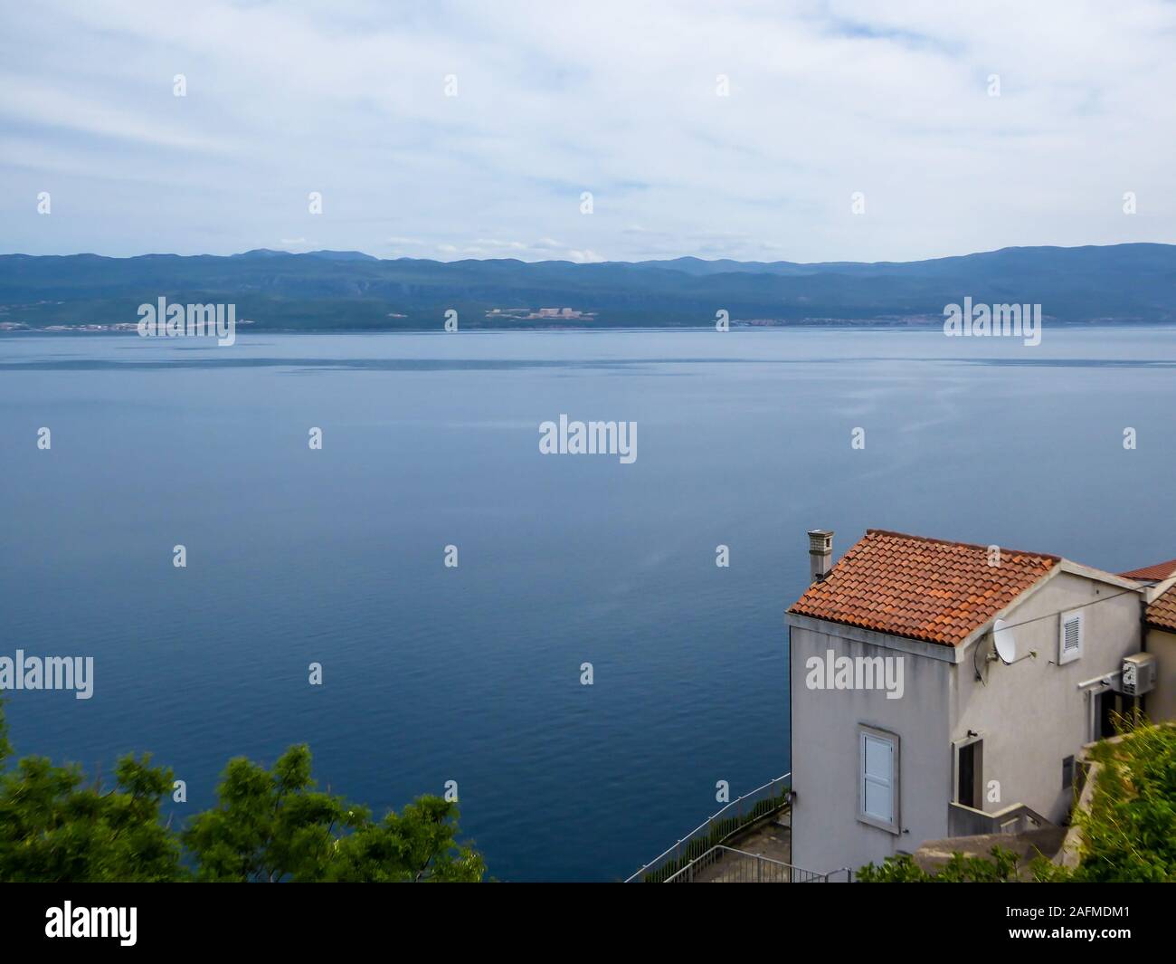 A sneak peak on a coastal line of Croatia from a hill. Steep slopes going down straight to the water. A little house on the side, with a direct view o Stock Photo