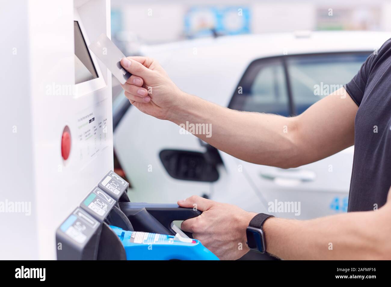 Man Charging Electric Vehicle Paying For Energy With Credit Card At