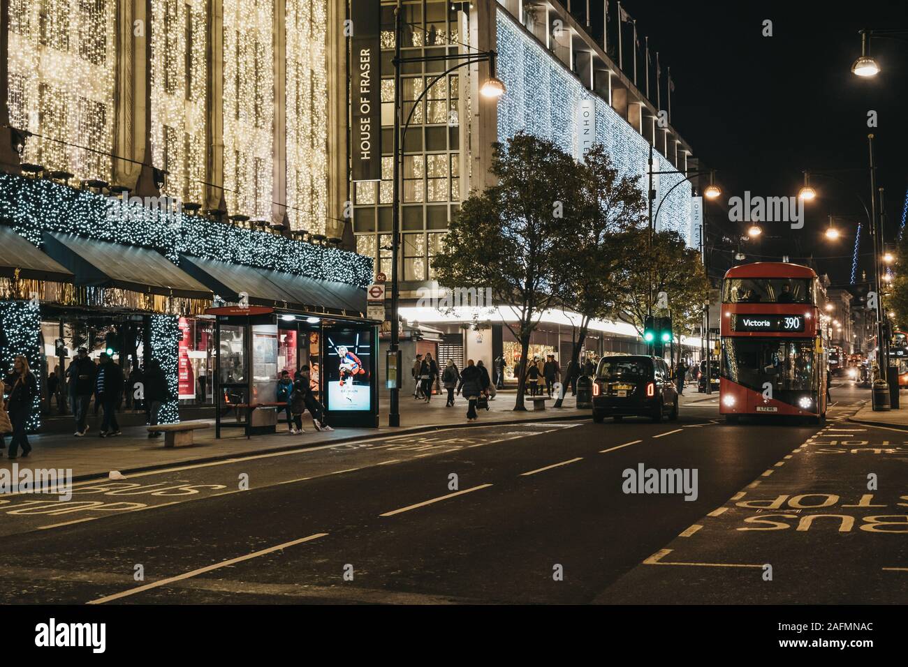 London, UK - November 17, 2019: Taxi and bus on Oxford Street in from of House of Fraser and John Lewis malls decorated with Christmas lights. Oxford Stock Photo