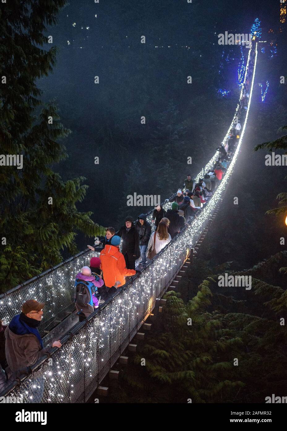The illuminated Capilano Suspension Bridge at night with people crossing Stock Photo
