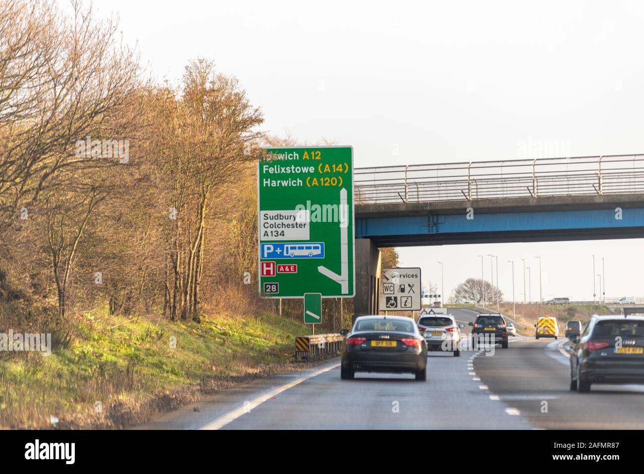 Road sign directions to Ipswich, Felixstowe, Harwich, Sudbury, Colchester with vehicles driving on a stretch of A12 duel carriageway, Essex, UK. Stock Photo