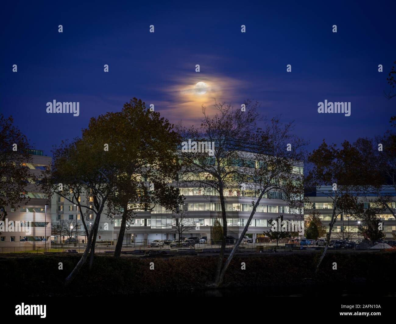 Office Building at night with full moon Stock Photo