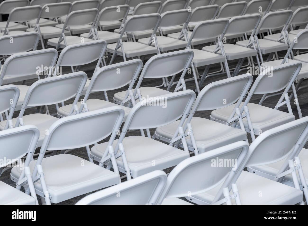 Rows of white padded folding chairs in auditorium Stock Photo Alamy