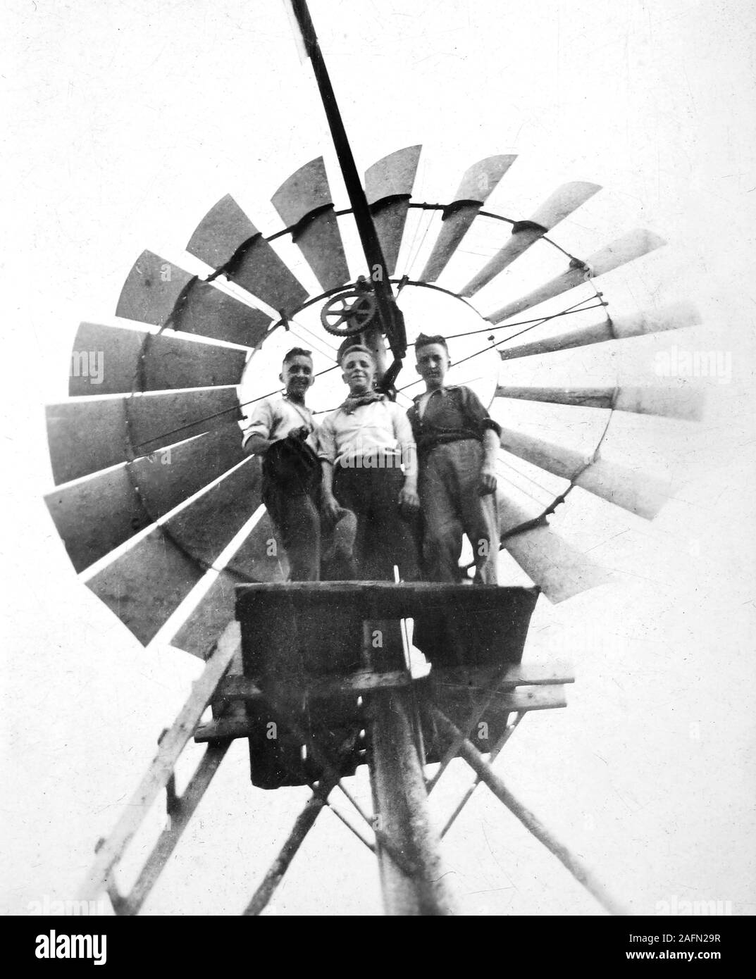 Three boys proudly pose on their homemade platform high atop a farm windmill in South Dakota, ca. 1938. Stock Photo