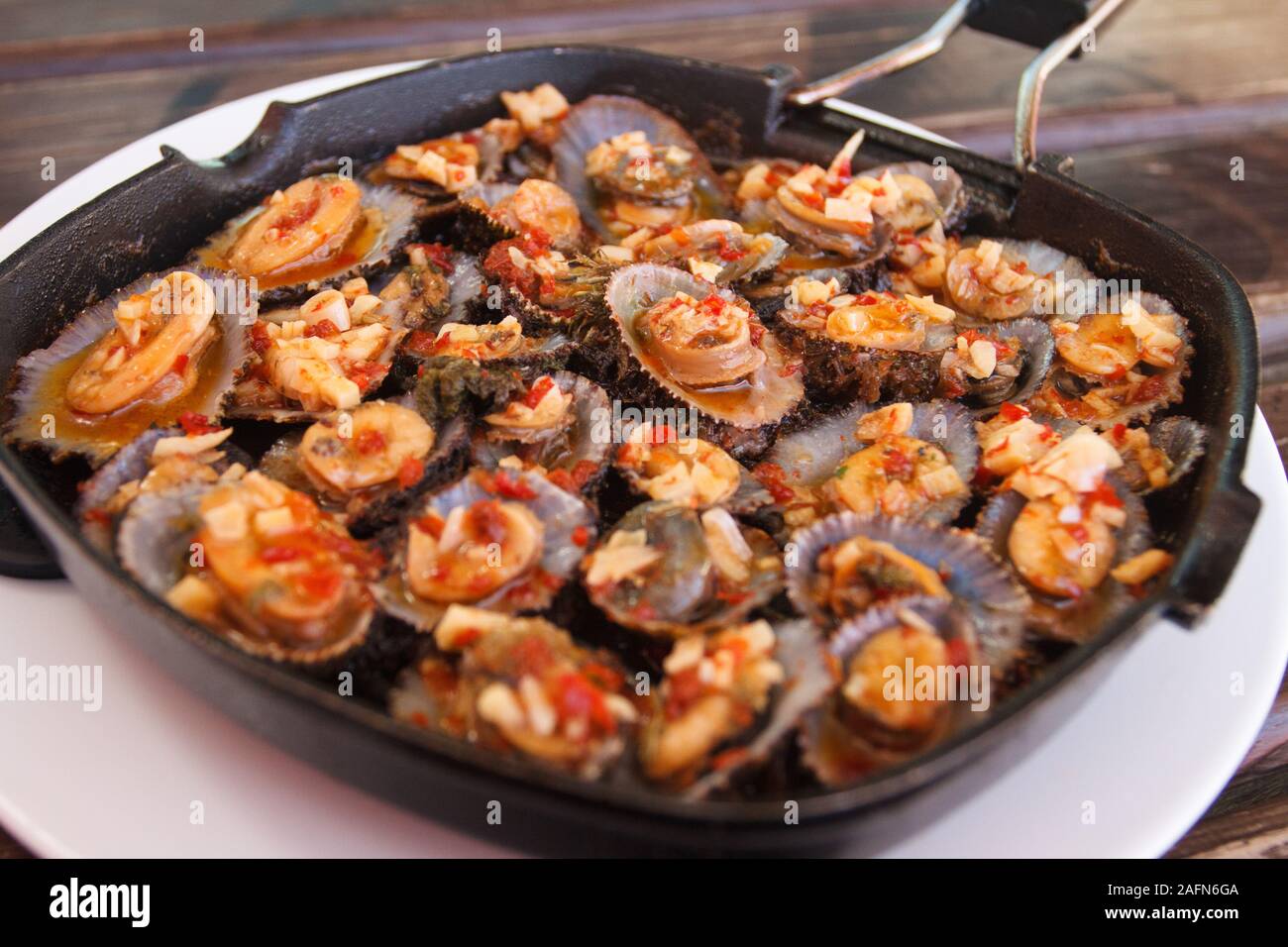 Grilled limpets or Lapas served in cast iron pan, A delicacy of Azores islands. Stock Photo