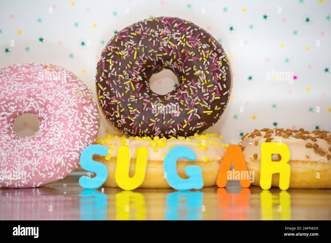 Group of delicious colorful glazed donuts near colorful background with the word sugar Stock Photo