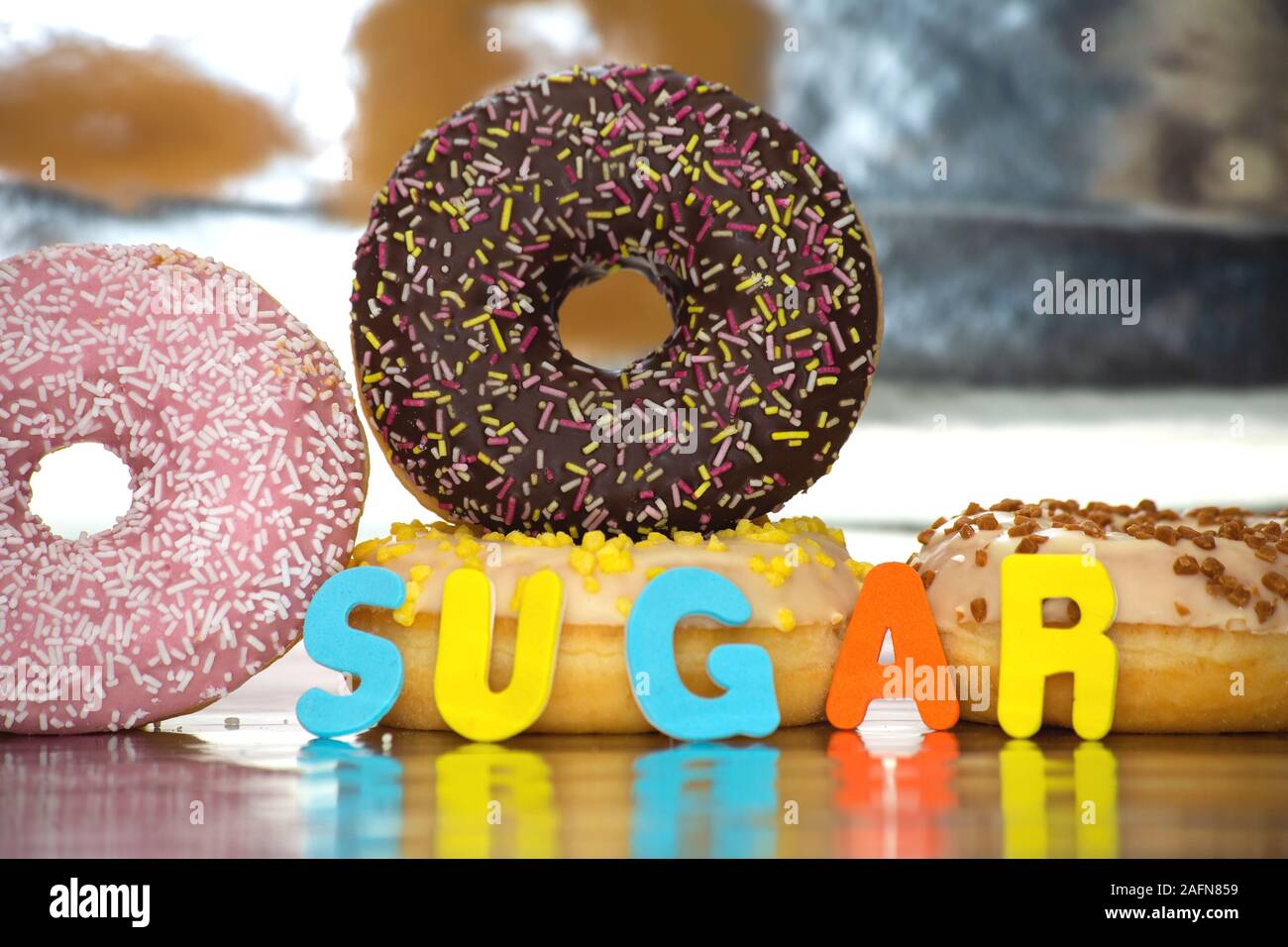 Group of delicious colorful glazed donuts near colorful background with the word sugar Stock Photo