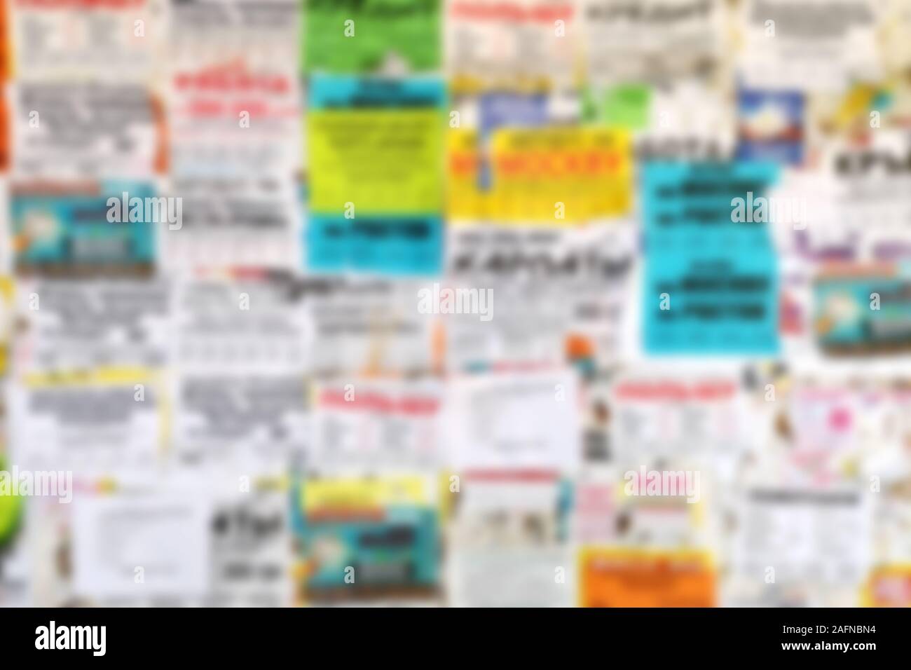 Blurred background of bulletin board outside. Bulletin board filled with paper notices. Stock Photo