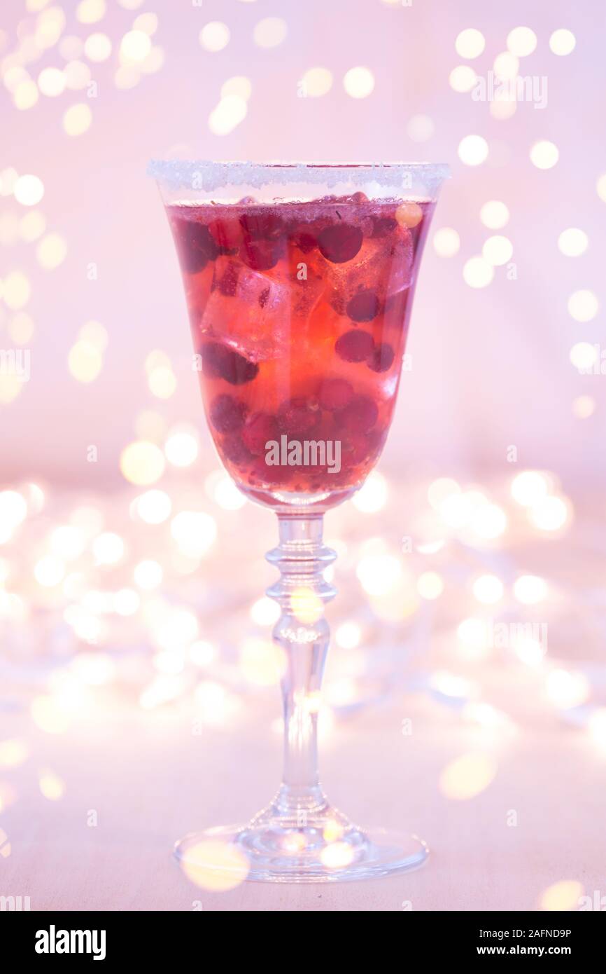 Glass of champagne and cranberry cocktail, macro. Lightweight background. Christmas mood. Vintage style. Shifted white balance, warm lilac tone. Vertical with gentle festive holiday bokeh Stock Photo