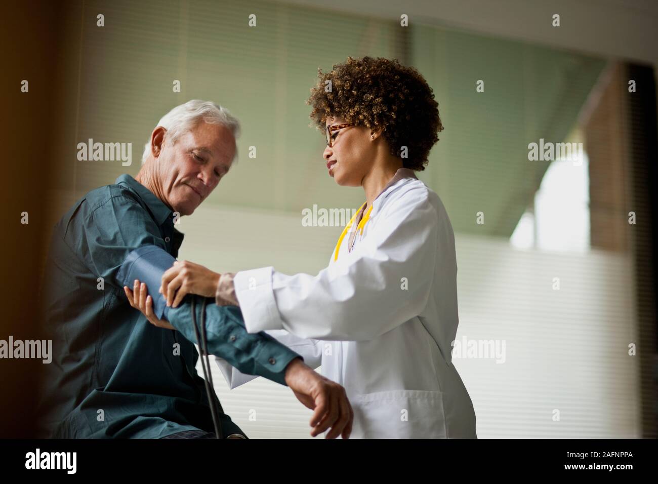 Female doctor taking patient's blood pressure. Stock Photo