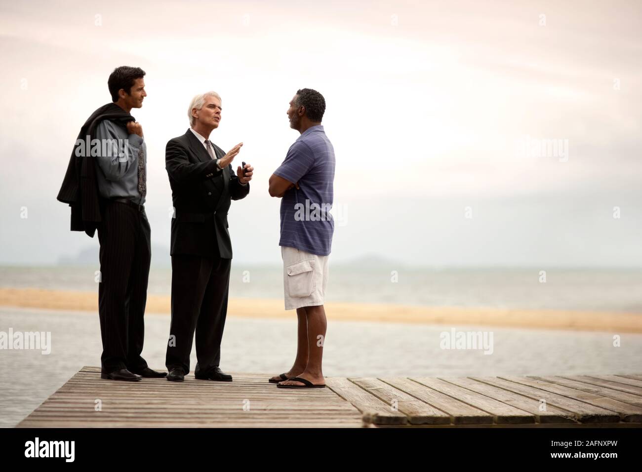 Three men having a discussion on a jetty. Stock Photo
