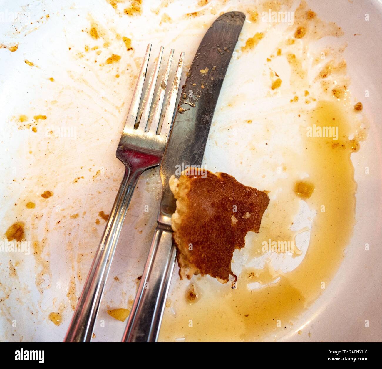 An empty, dirty plate at the end of a meal of American style pancakes with maple syrup. Stock Photo