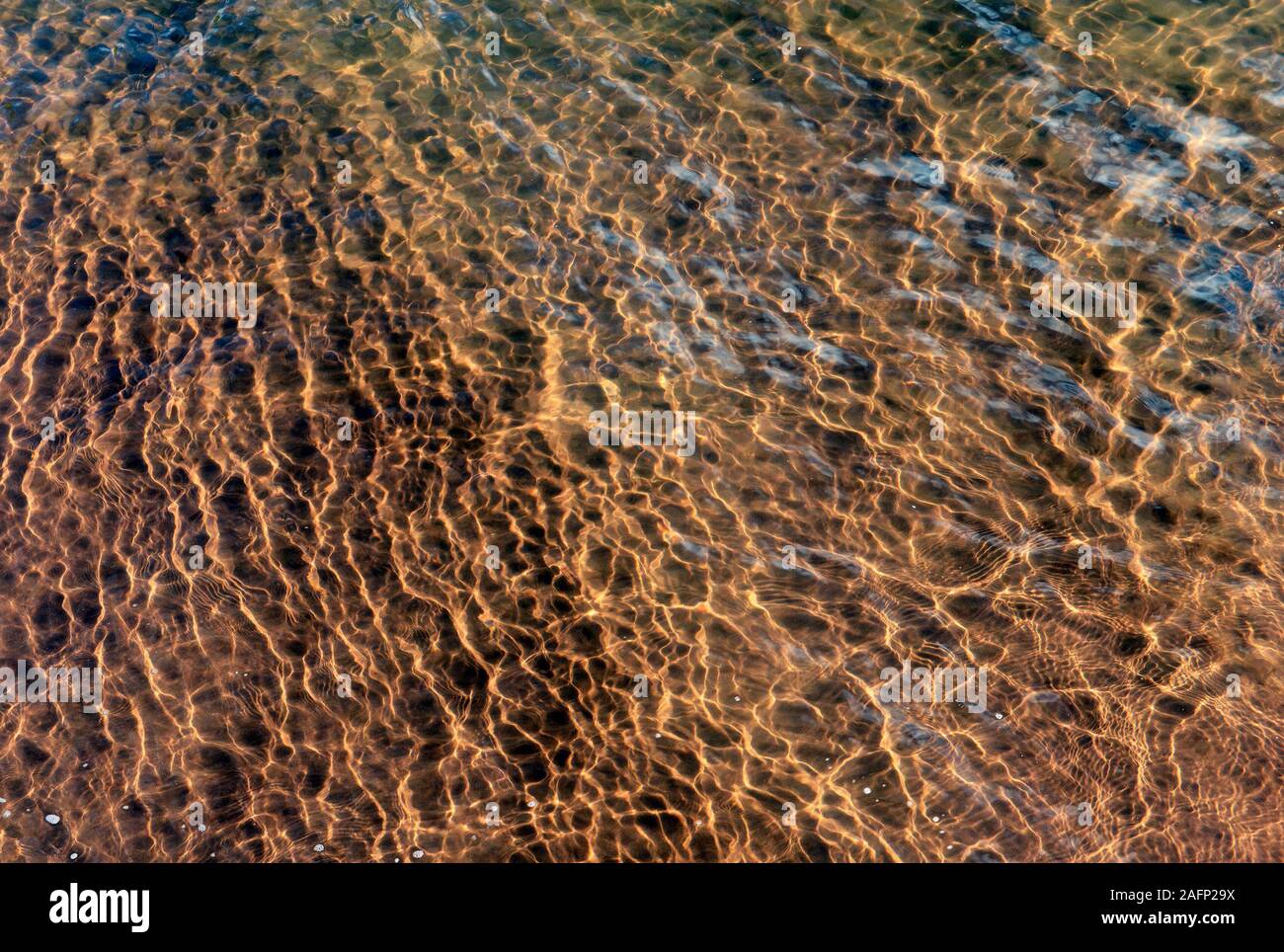 Reflective patterns in shallow water at Goodrington Sands beach near Paignton, Devon, UK Stock Photo