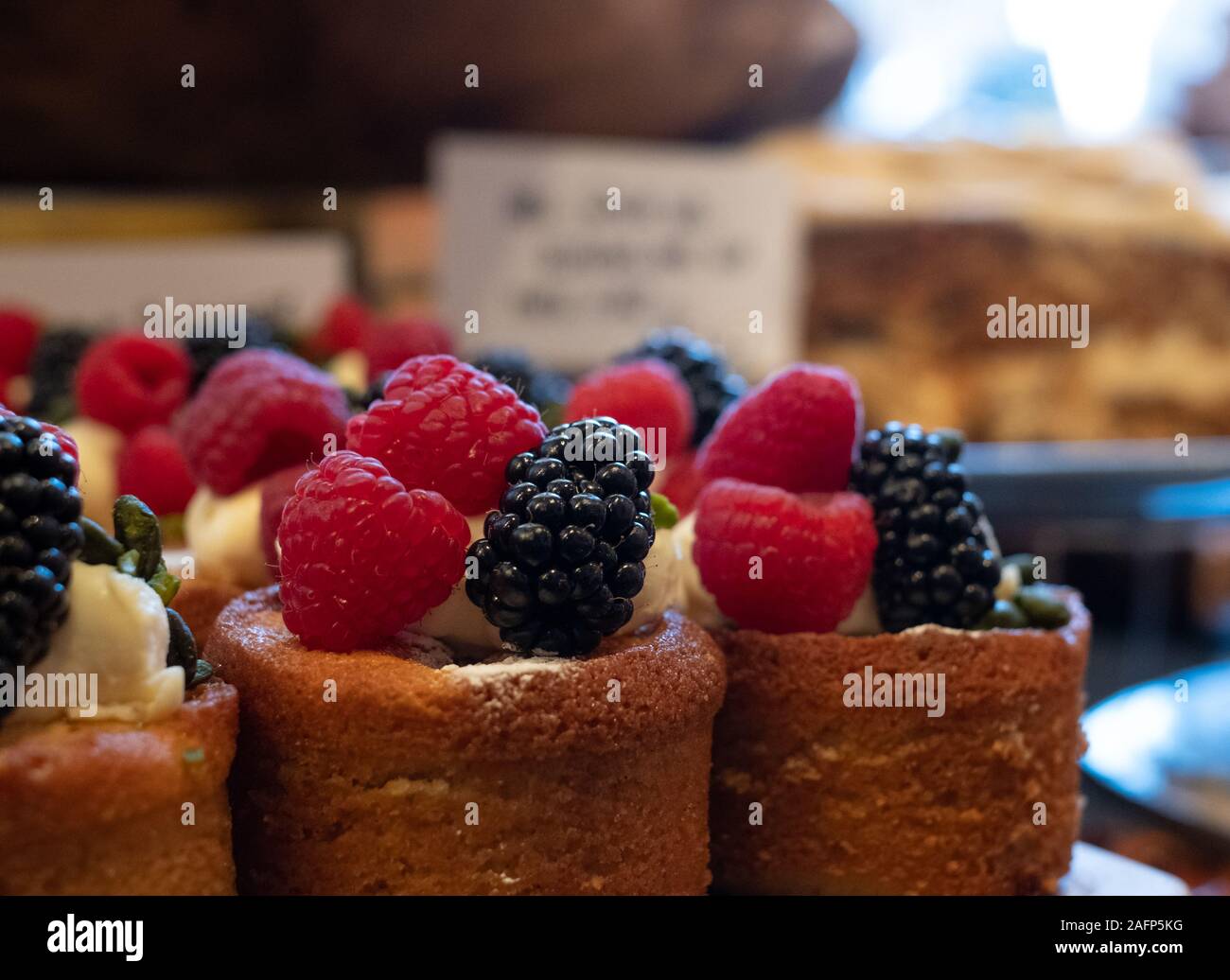 Cakes with berries on top, on display in the Ottolenghi restaurant and shop in Spitalfields, London UK Stock Photo