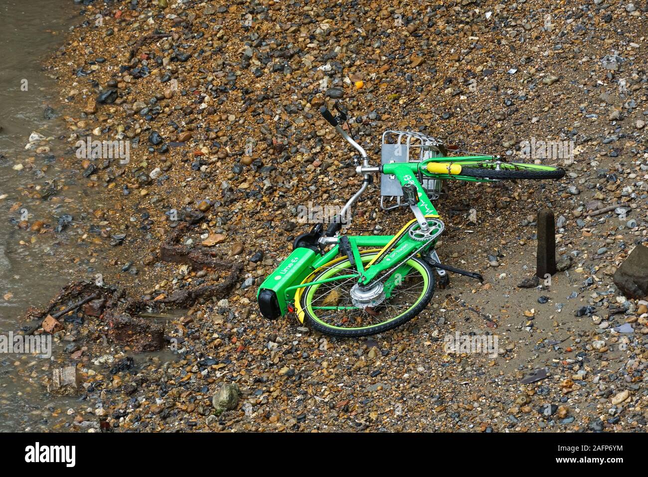 Dockless Lime e-bike, electric bicycle dumped on the bank of the River Thames, London, UK Stock Photo