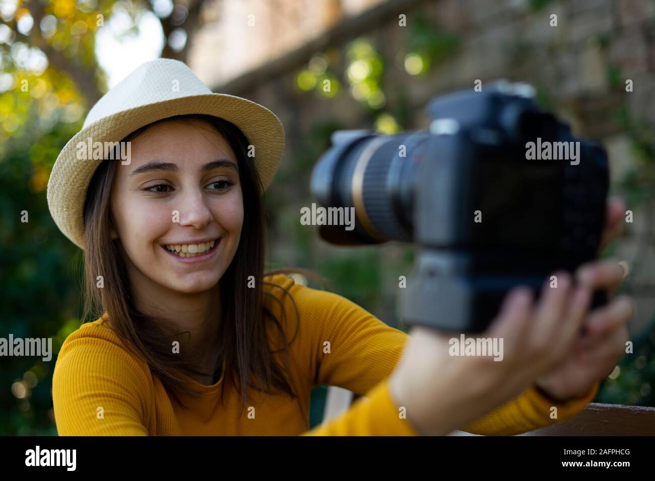 Woman vlogger and influencer with hat recording a video with a reflex camera for her blog. Concept of social networks. Stock Photo