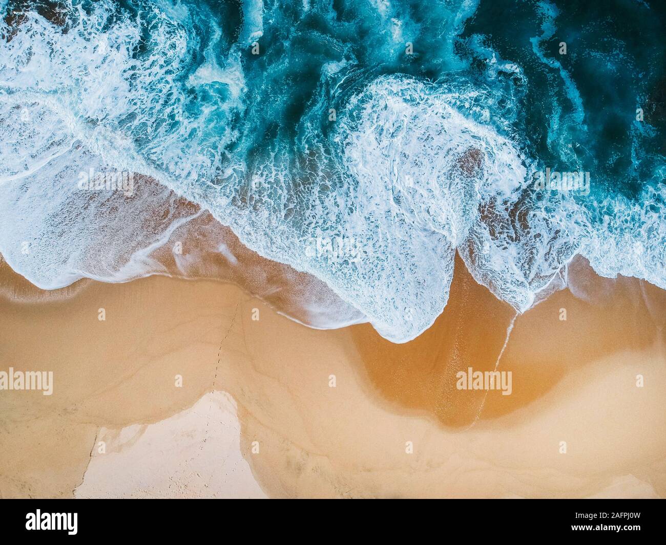 drone aerial view of ocean surf crashing on empty beach blue Stock Photo