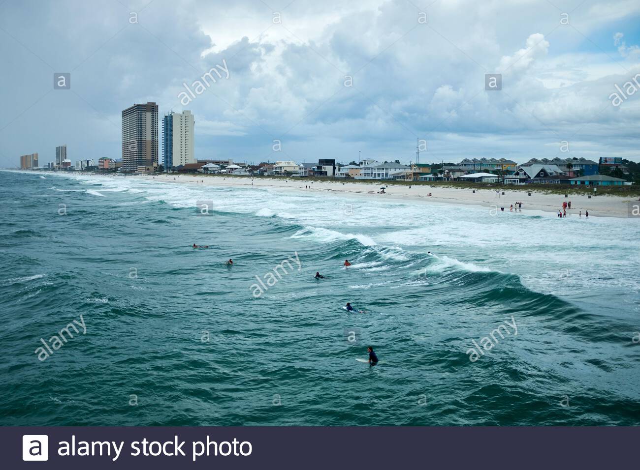 Surfers Waiting For The Next Wave Break With Hotels Behind
