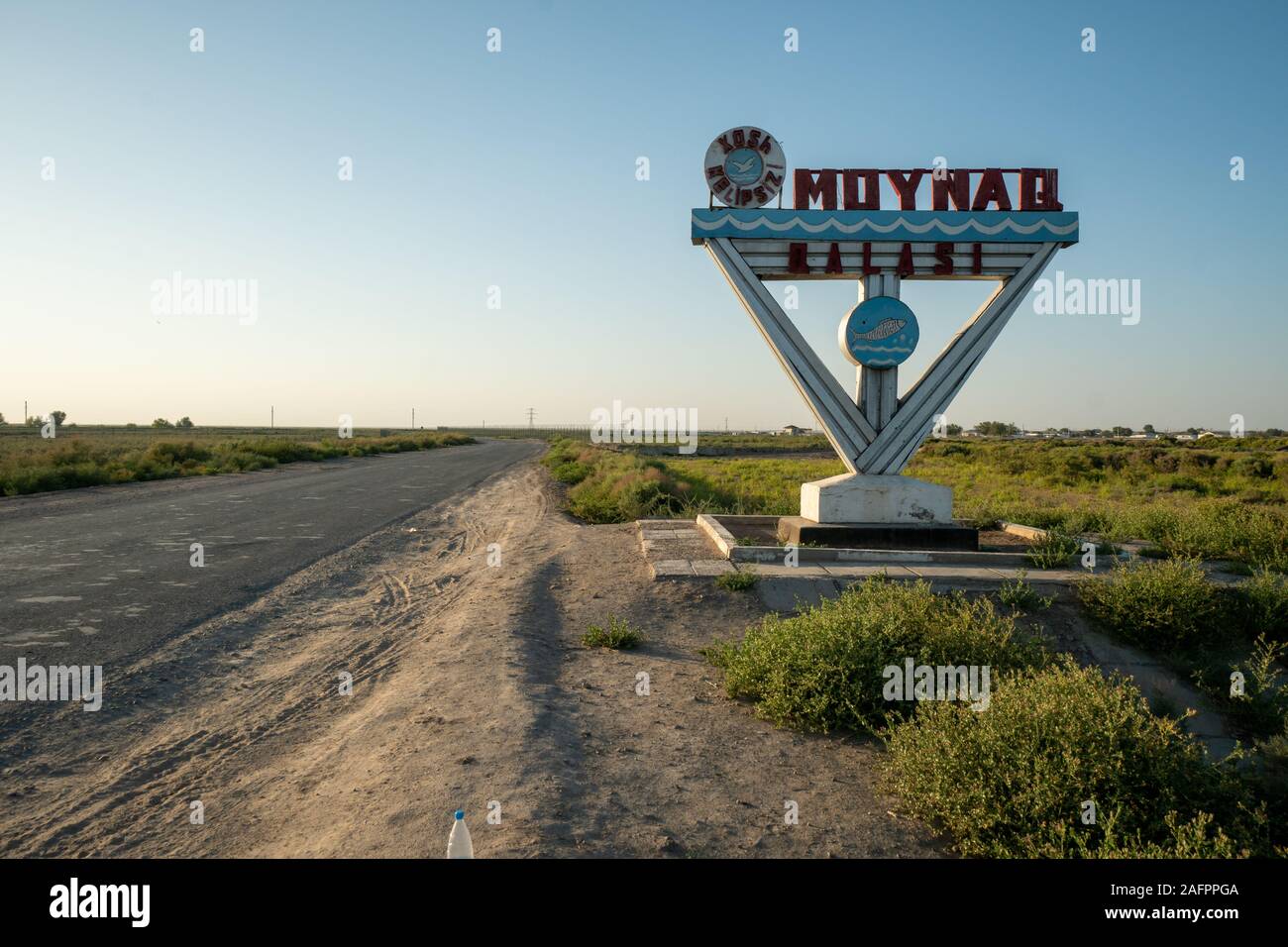 Signpost at the entrance to the tow of Muynak in Uzbekistan (saying 'Moynaq Qalasi' / 'Muynak castle'). It used to be an the shore of the Aral Sea and Stock Photo