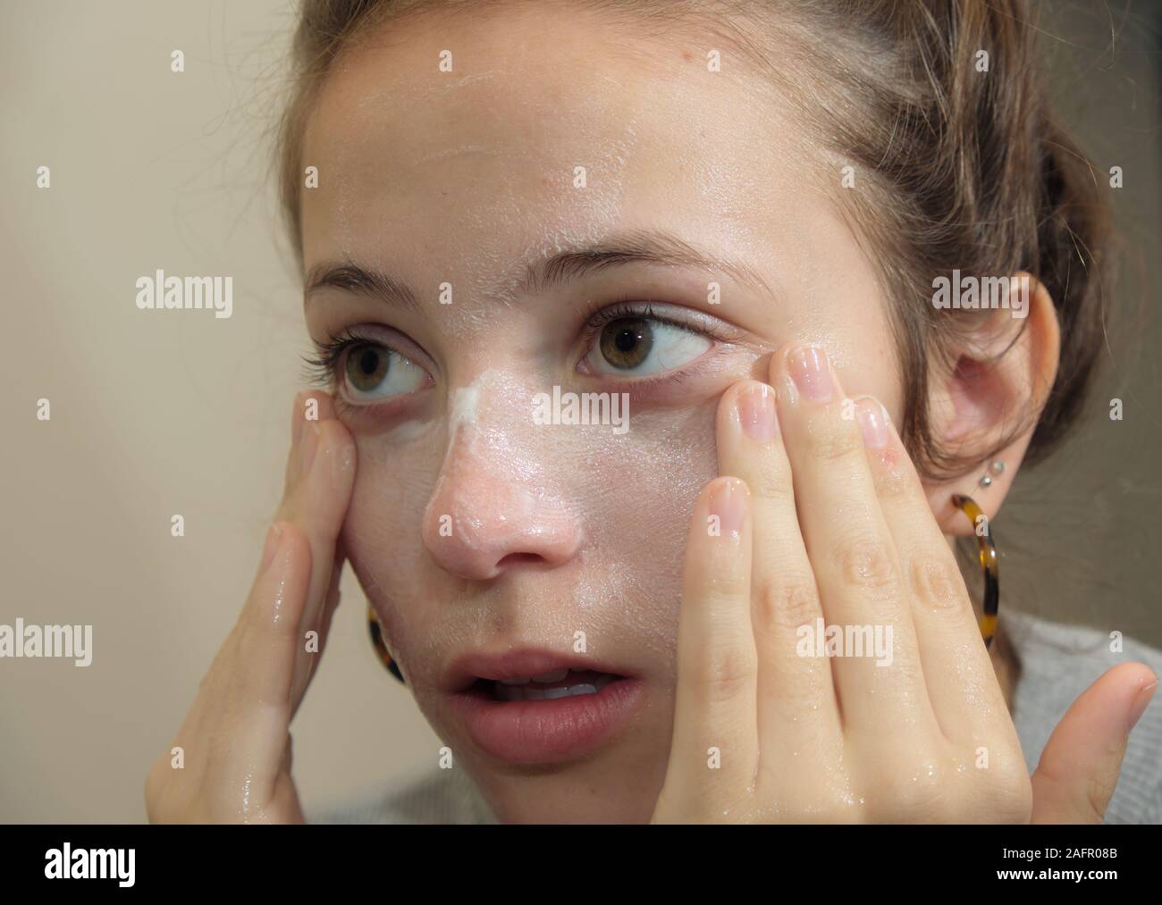 Teenage girl washing her face in bathroom Stock Photo