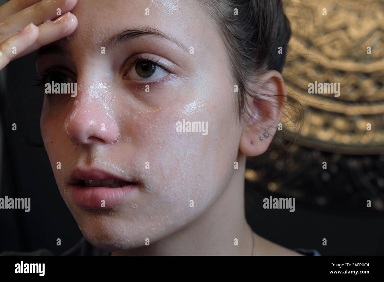 Teenage girl washing her face in bathroom Stock Photo
