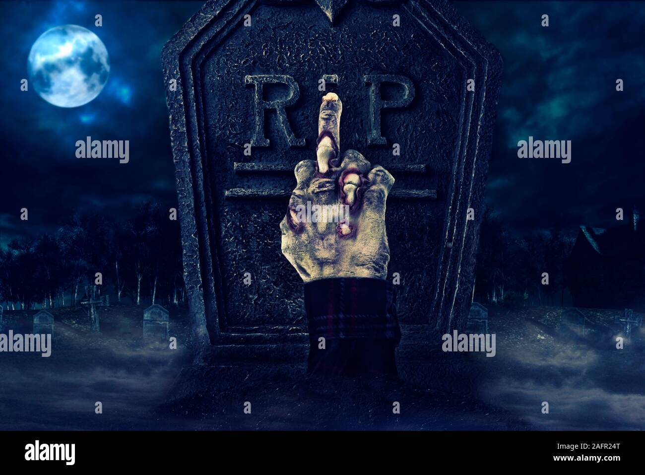 Zombie hand showing middle finger in front of tombstone, creepy cemetary in the background. Stock Photo