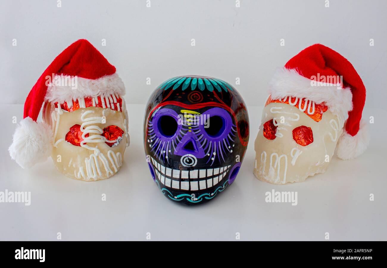 White Traditional Mexican sugar skulls with Santa hats. Mexican Christmas.(calaveritas de azucar para navidad en México) mix cultures. Stock Photo