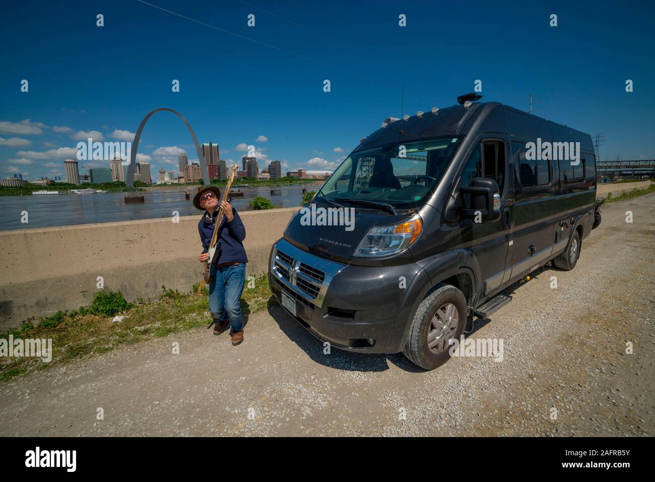 MAY 14, 2019, ST LOUIS, MO. USA Photographer and Bass Player Joe Sohm plays bass on Mississippi River front in front of St. Louis Arch and his RV Stock Photo