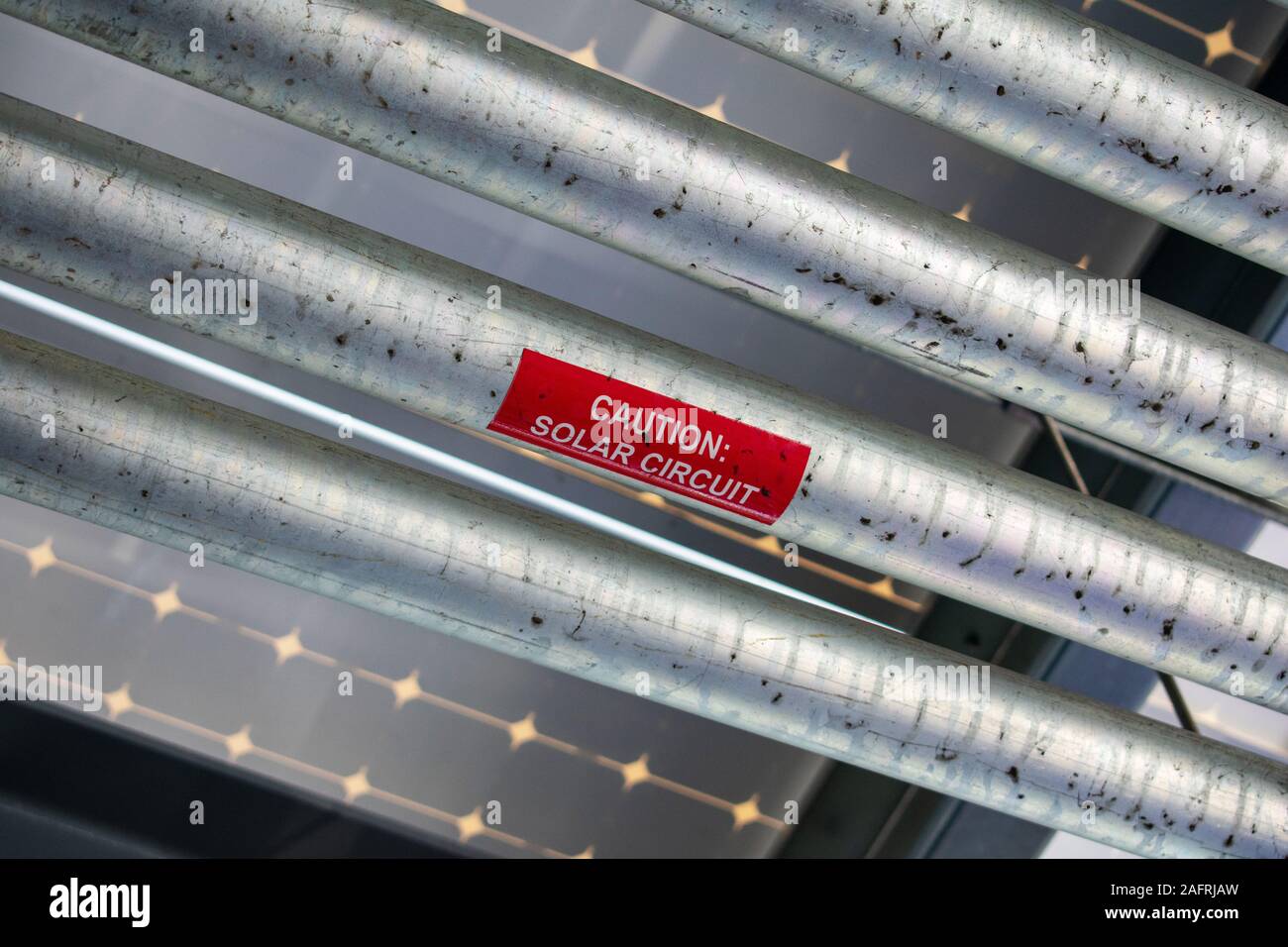 Caution Solar Circuit warning red sticker on dirty metal surface of solar circuit under a solar panels installed as canopy on top of parking garage Stock Photo