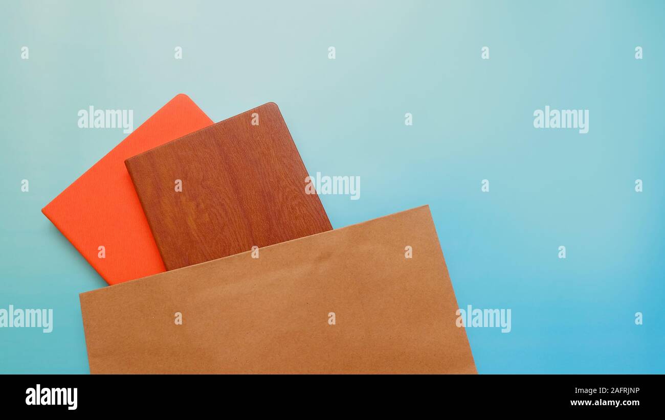 Two hard cover note books popping out from a brown paper bag, with copy space in the top right corner. Stock Photo