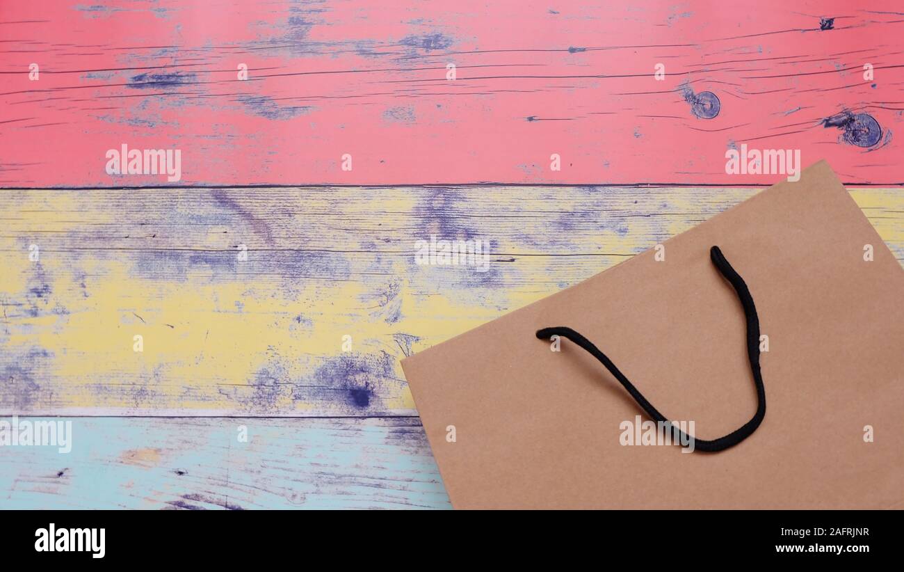 A brown paper bag on a colorful wooden background, with copy space in ...