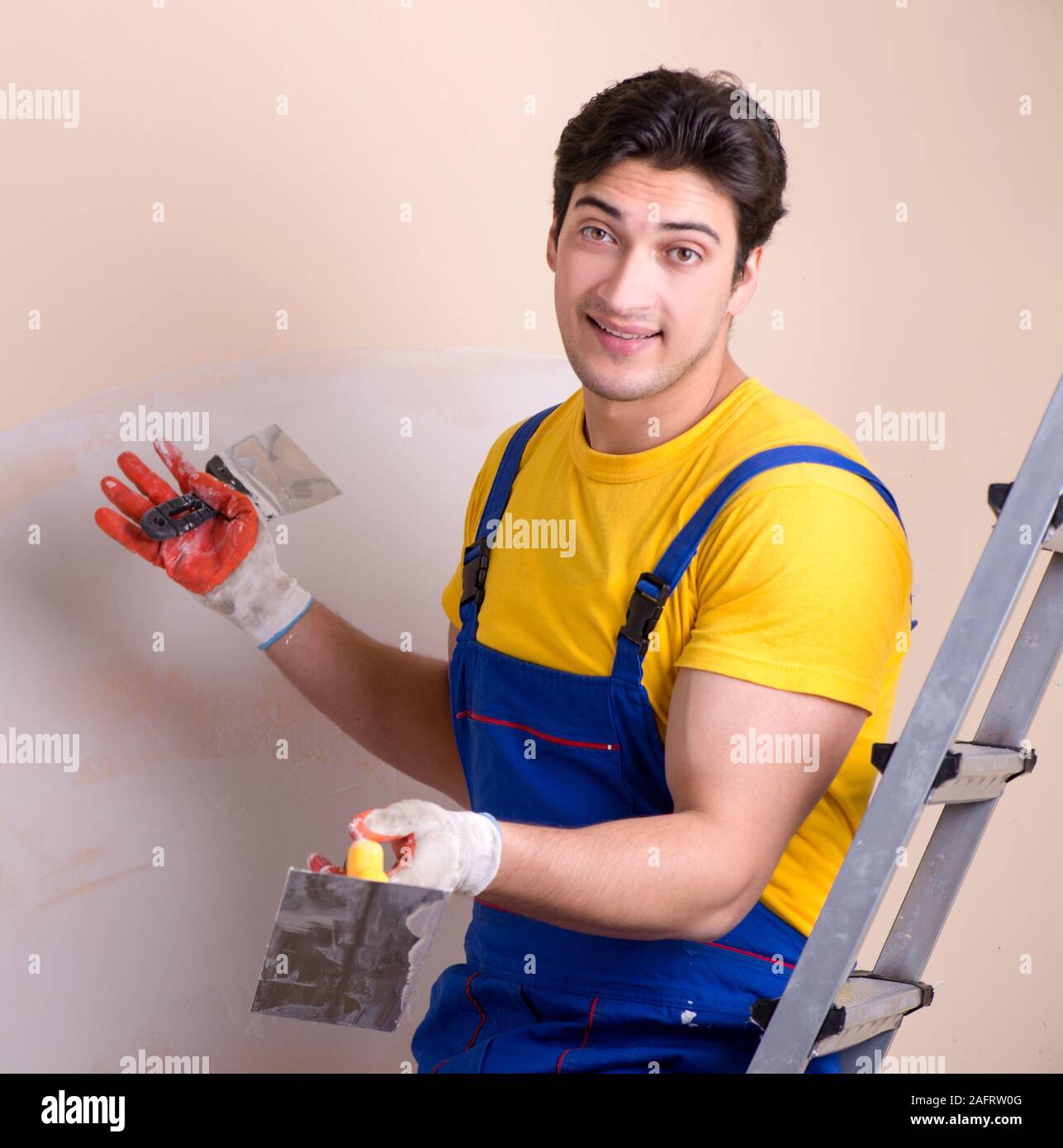 The young contractor employee applying plaster on wall Stock Photo