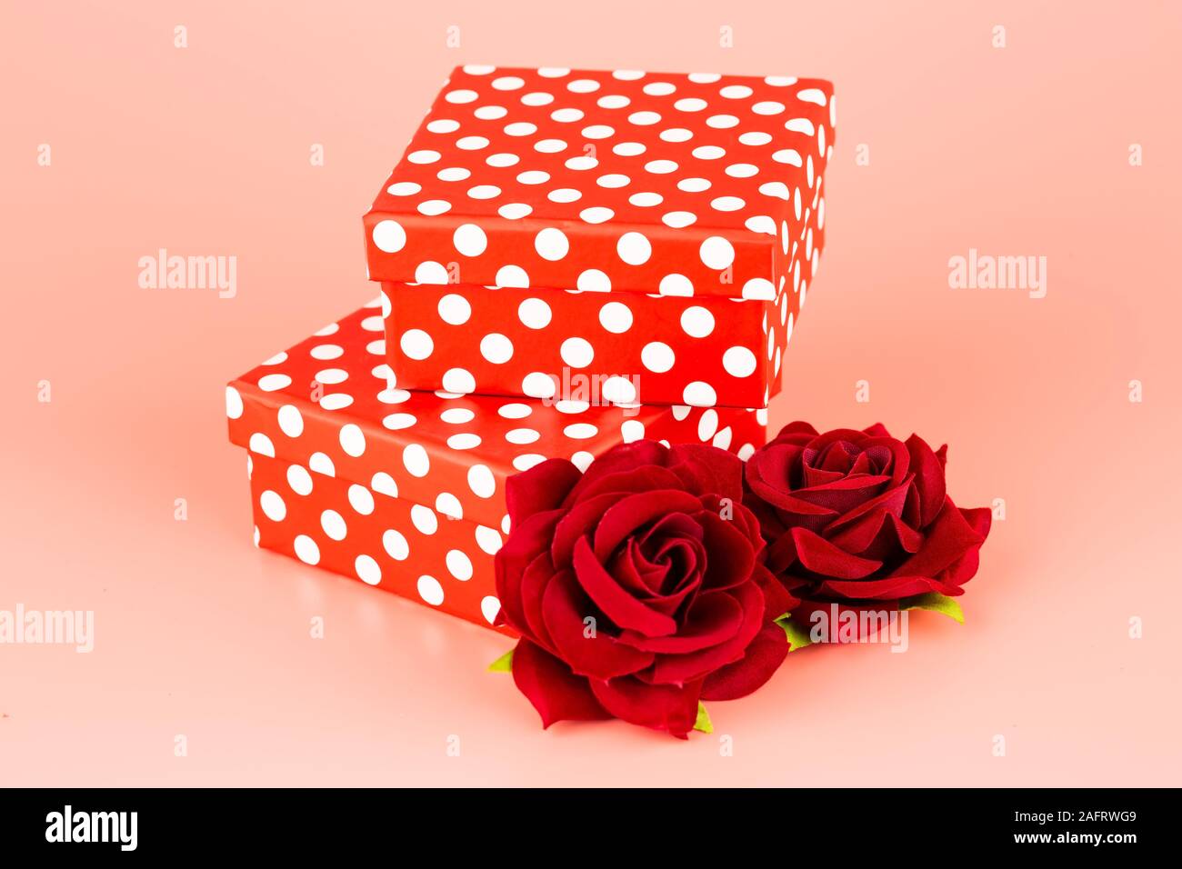 Two gift boxes and red roses isolated on pink background. Stock Photo