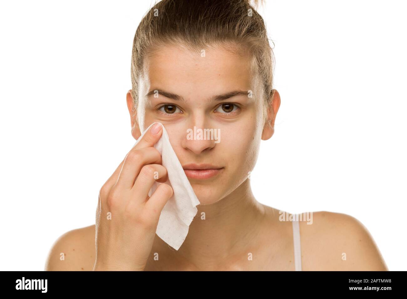 Young woman cleaning her face with wet wipe on white background Stock
