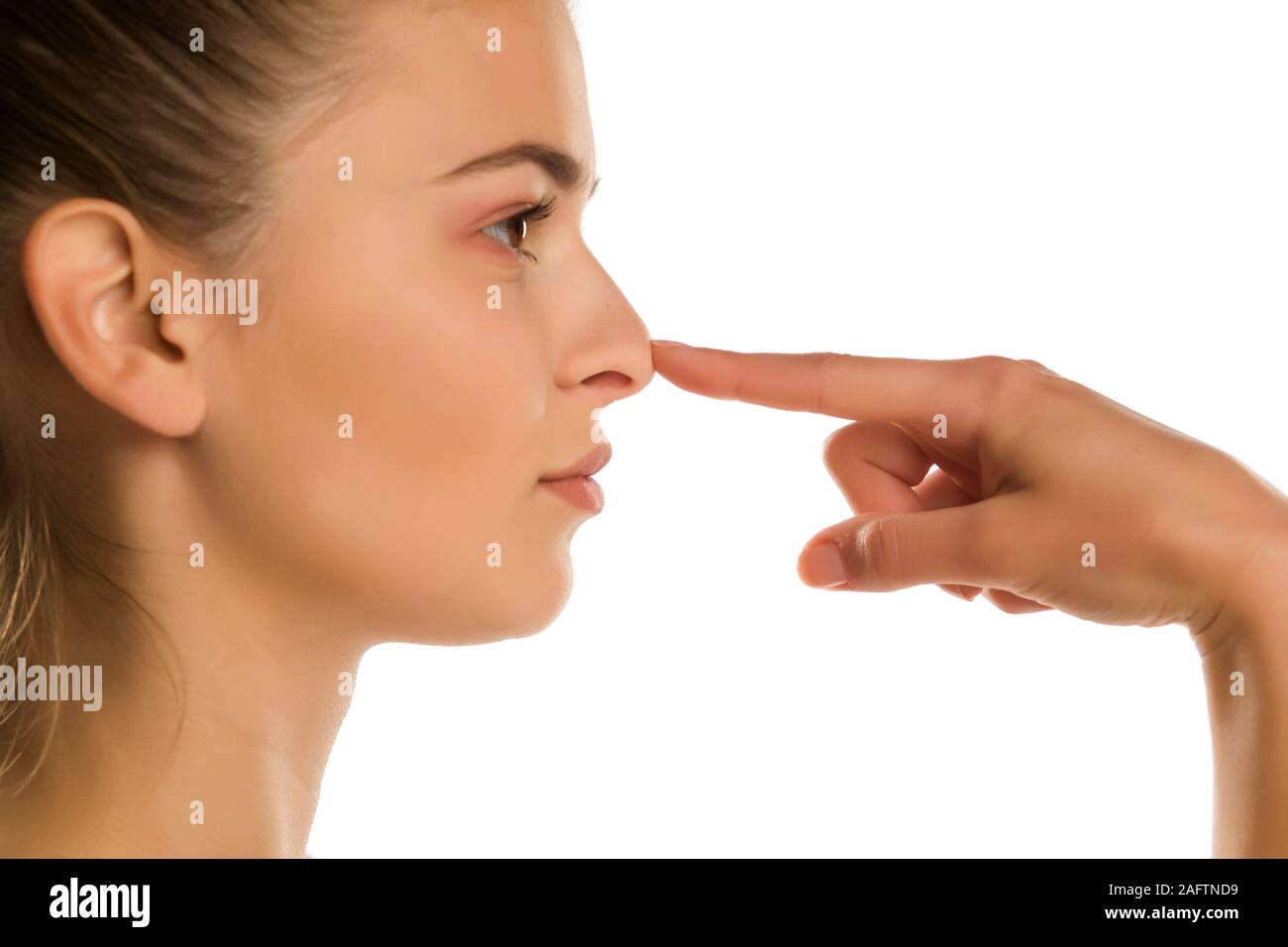 profile of young woman touches her nose on white background Stock Photo