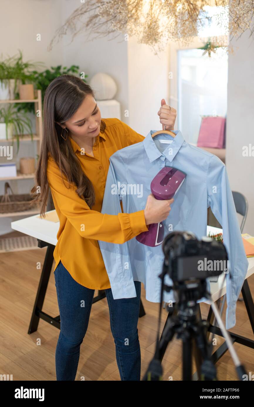 Nice young woman showing how to iron the shirt Stock Photo