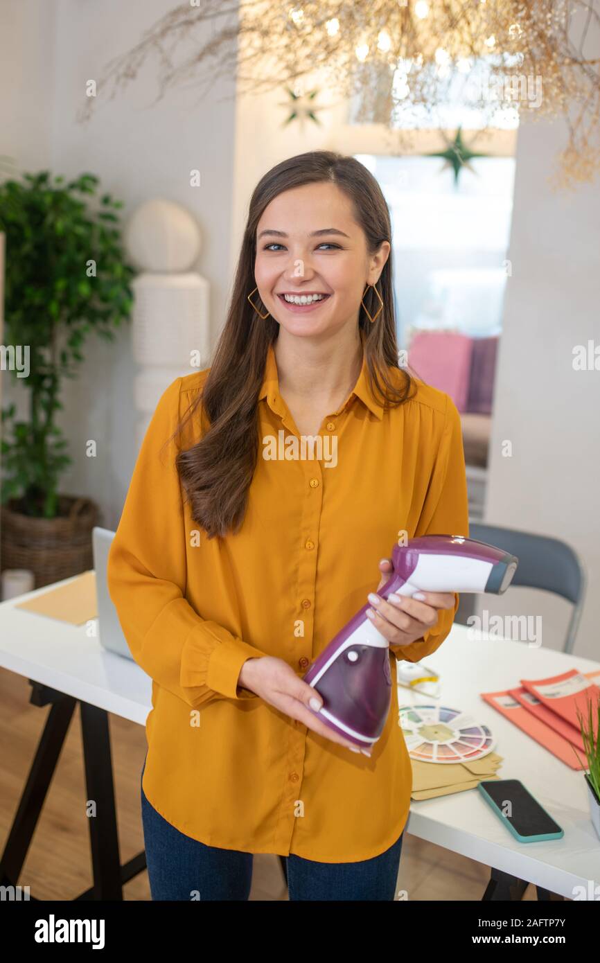 Pleasant smiling woman holding a steamer in her hand Stock Photo