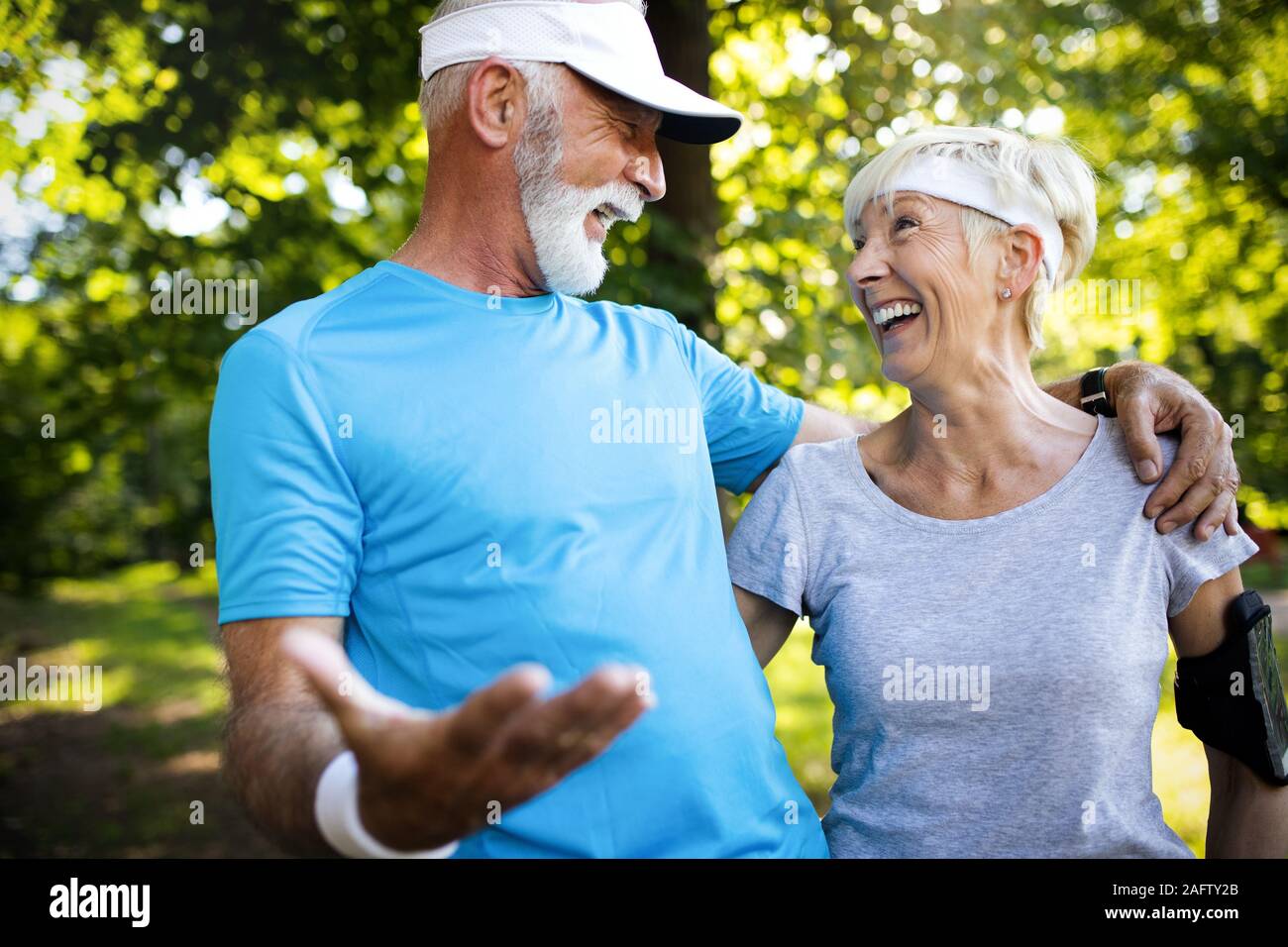 Beautiful senior couple running outside in forest Stock Photo
