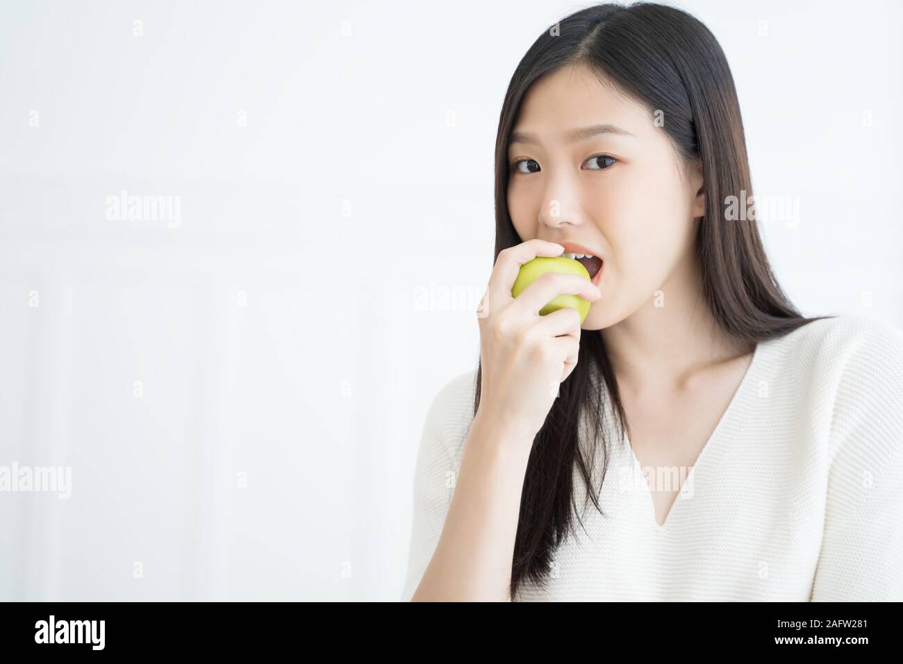 Young Asian woman bite green apple show Strong teeth Stock Photo