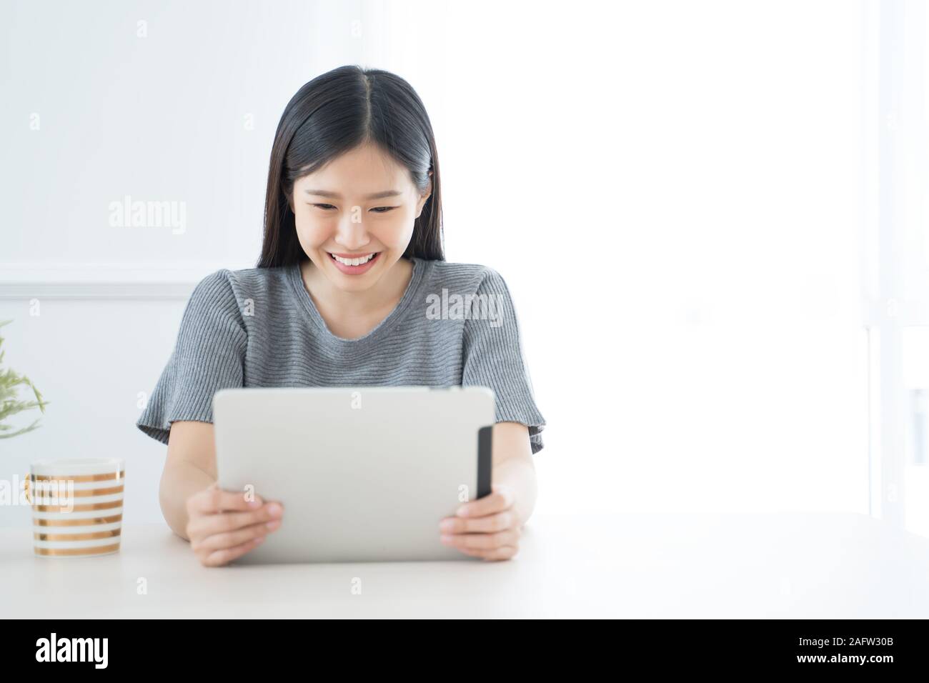 Young Asian woman using tablet at home and having breakfast in the morning .She reading on tablet. Stock Photo