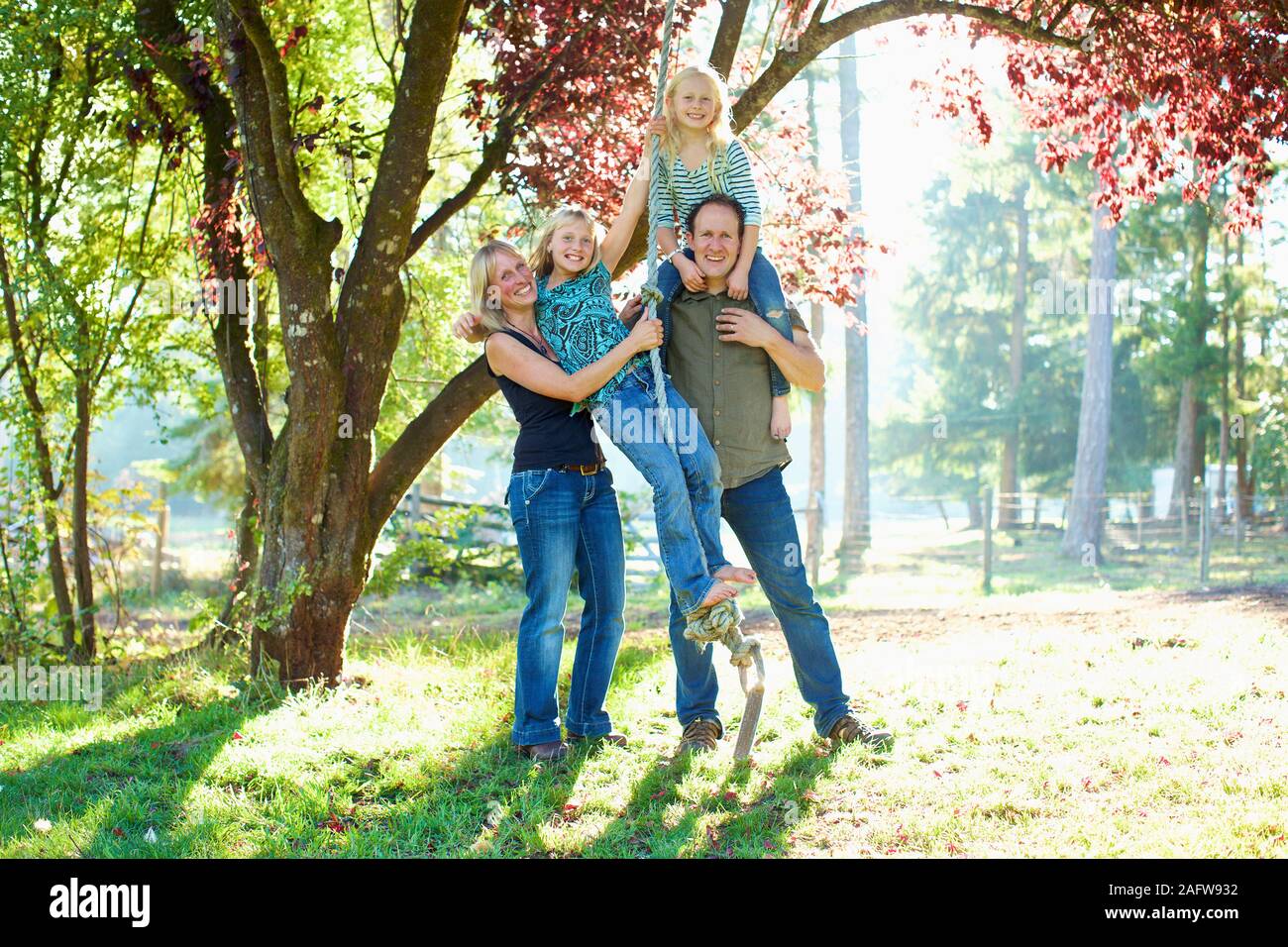 Portrait happy family on rope swing in sunny autumn park Stock Photo