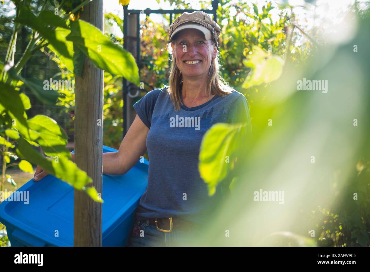 Portrait confident smiling farmer in sunny vegetable garden Stock Photo