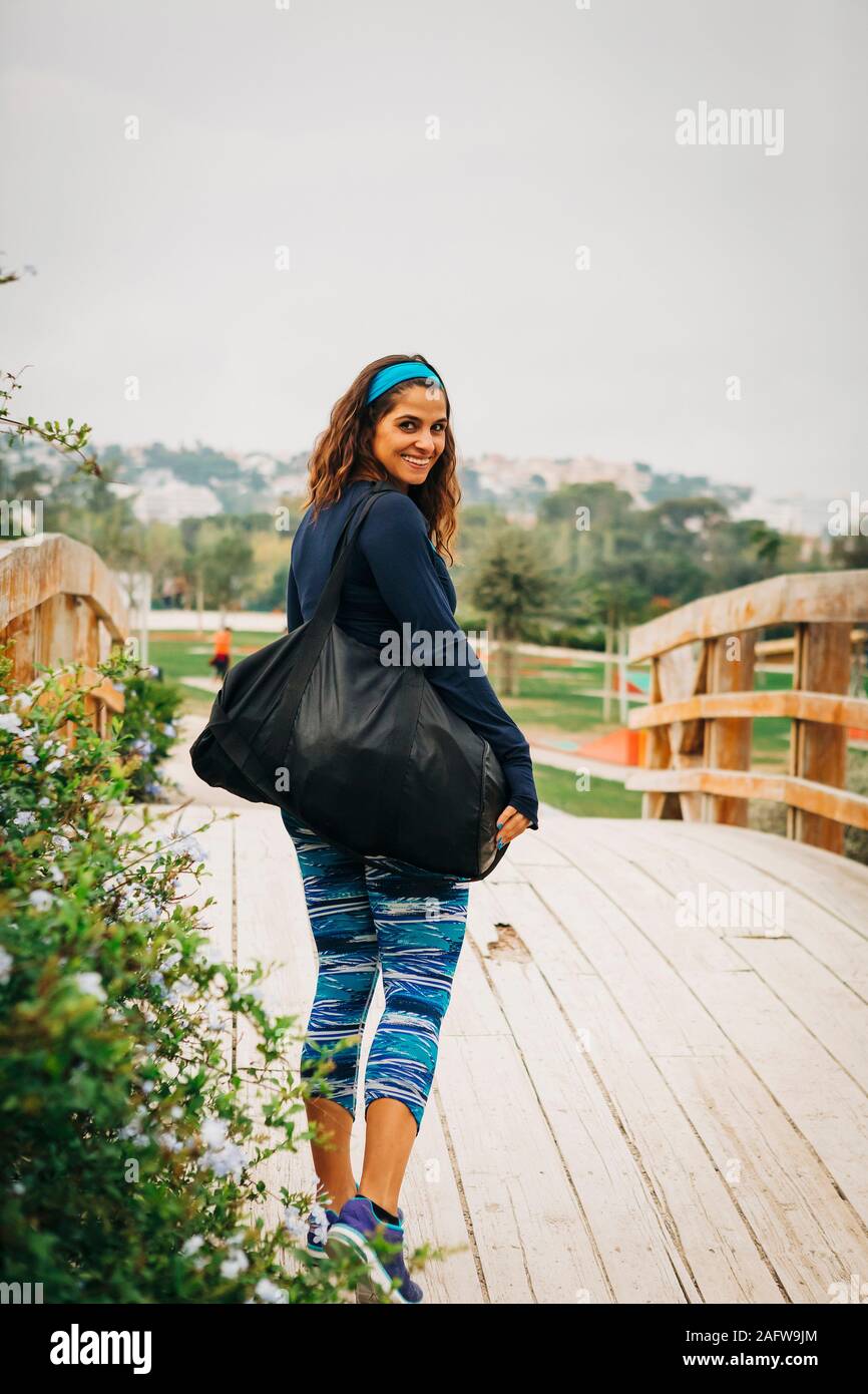 Portrait confident female personal trainer walking over footbridge in park Stock Photo