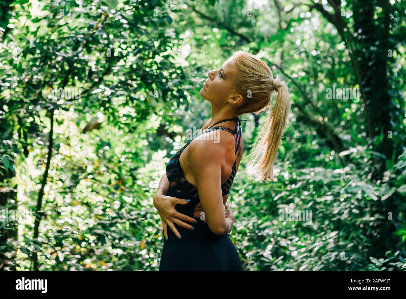 Fit female personal trainer stretching in forest Stock Photo