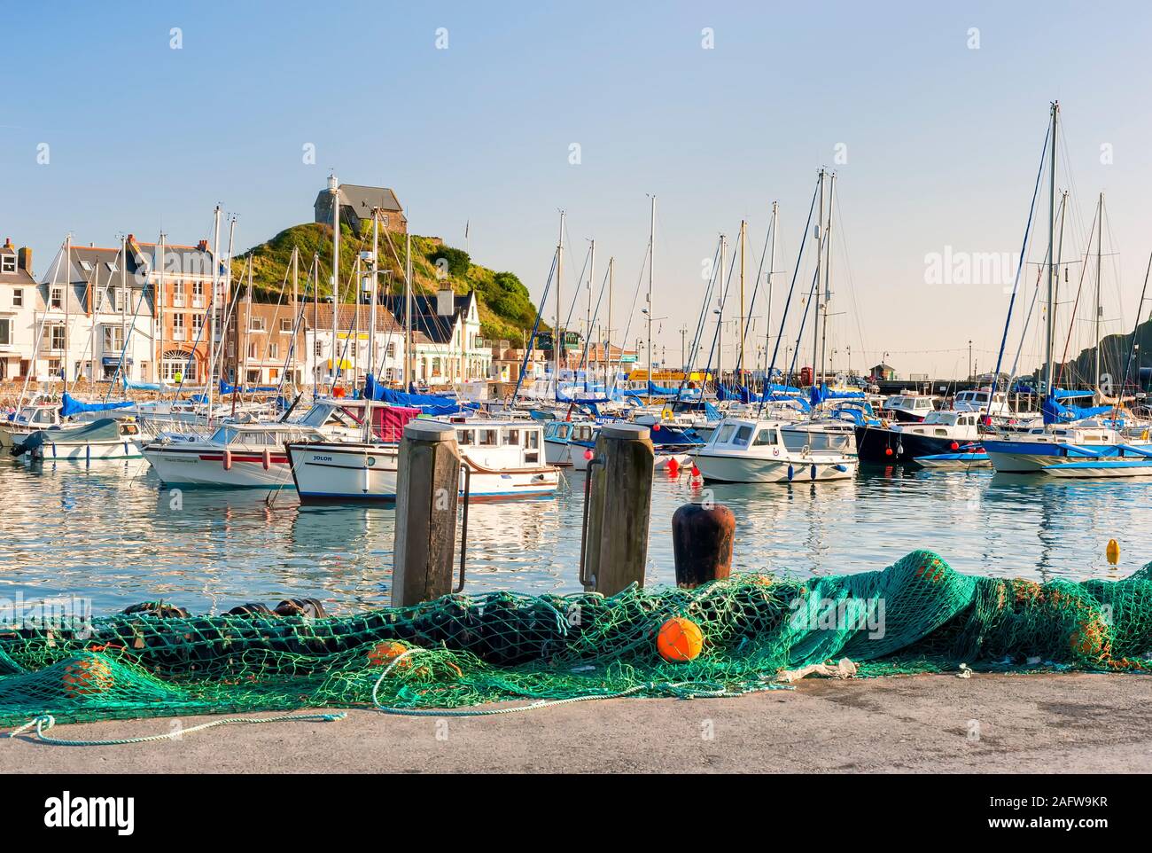 Ilfracombe Harbour with fishing nets on the side with yachts boats and fishing boats in the harbour with views to St Nicholas Chapel on Lantern Hill Stock Photo