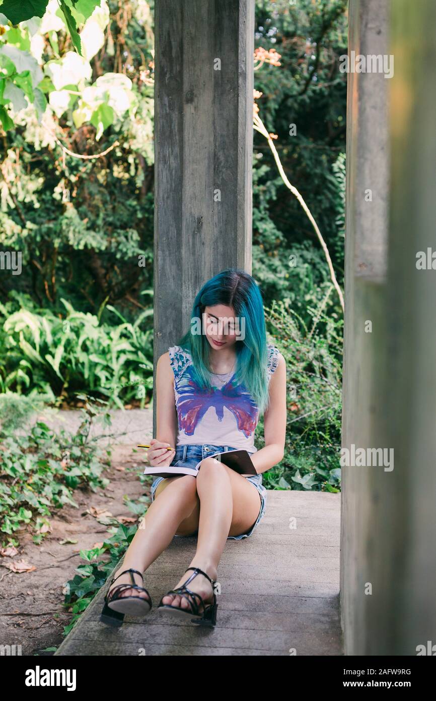 Young woman writing in journal in park Stock Photo