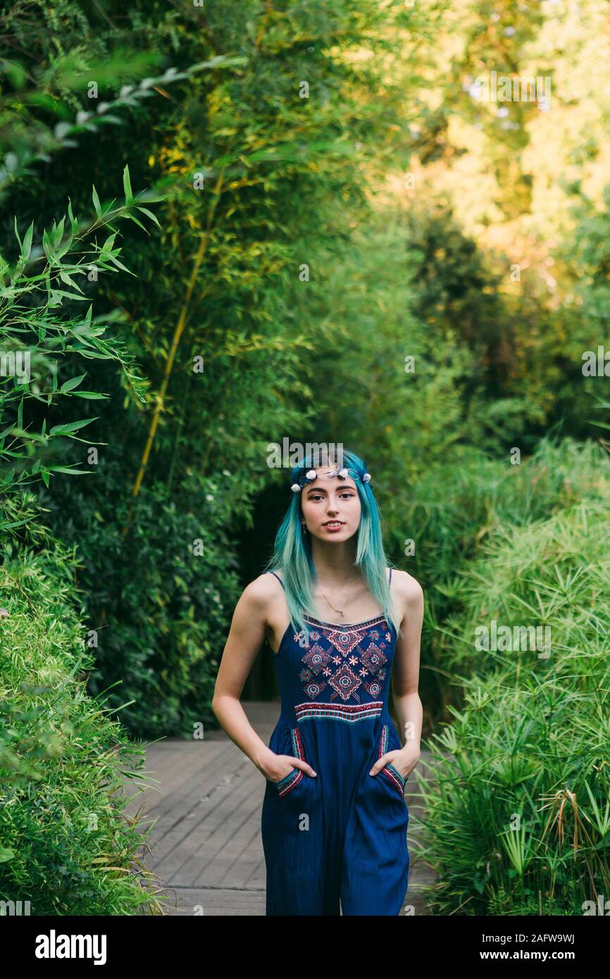 Portrait young woman with blue hair on footpath in lush park Stock Photo