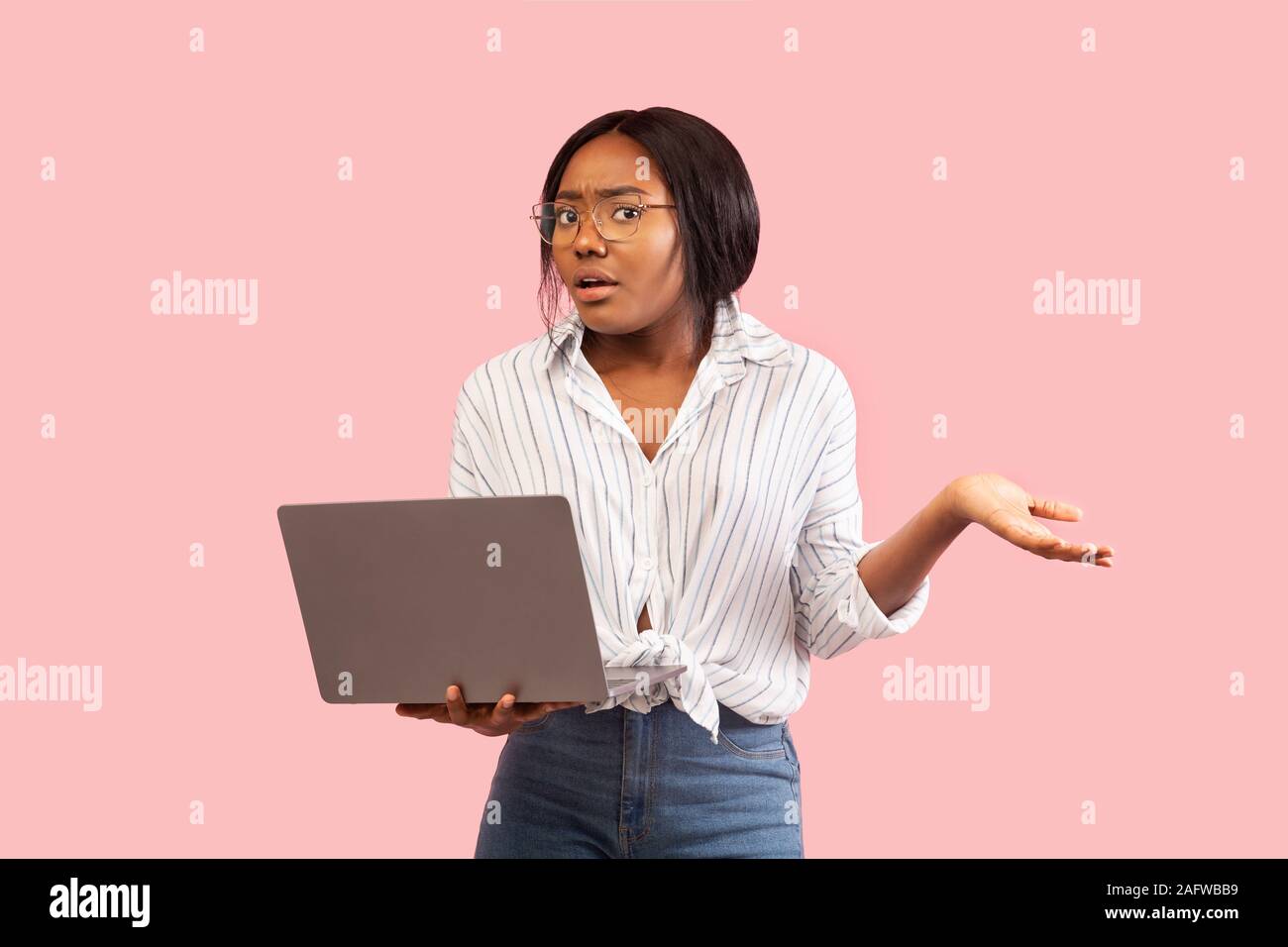 Discontented Girl Holding Laptop Shrugging Shoulders Having Problem, Studio Shot Stock Photo