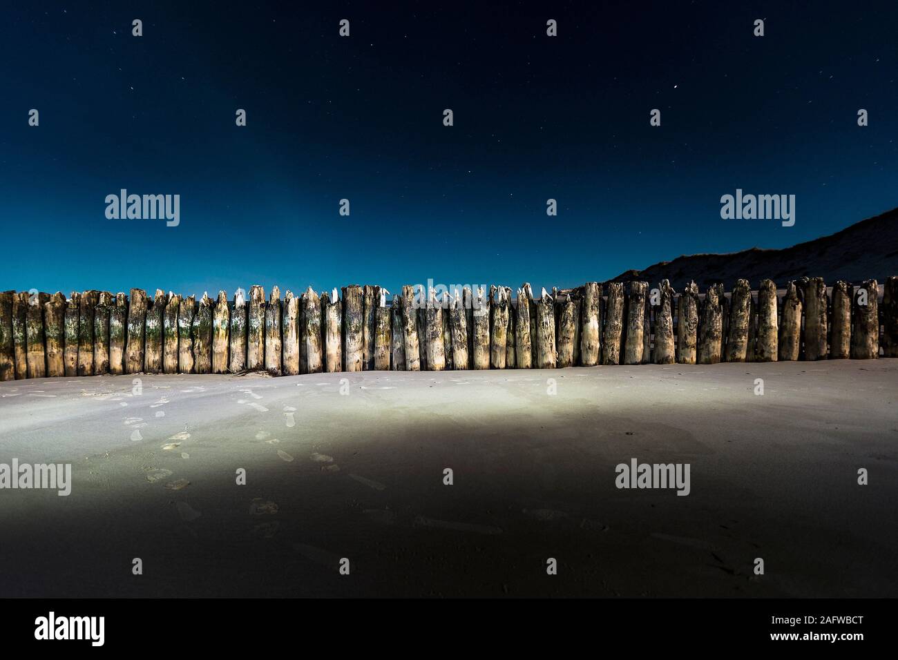 Sheet piling wall illuminated on beach at night Stock Photo