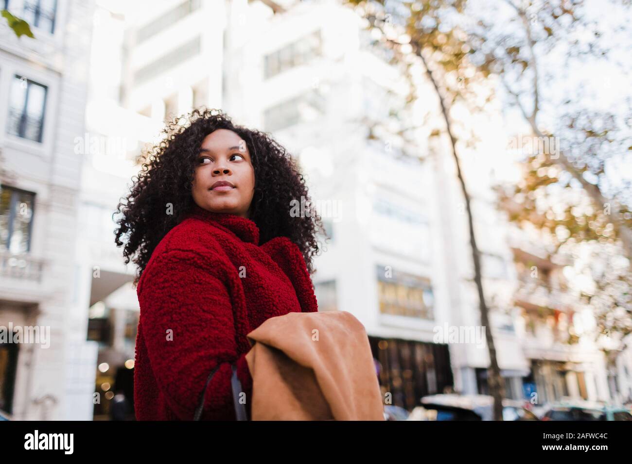 Young woman looking over shoulder on urban street Stock Photo